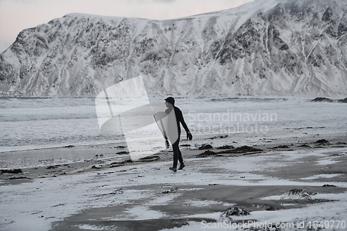 Image of Arctic surfer going by beach after surfing