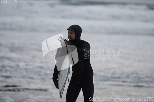 Image of Arctic surfer going by beach after surfing