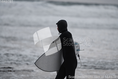 Image of Arctic surfer going by beach after surfing