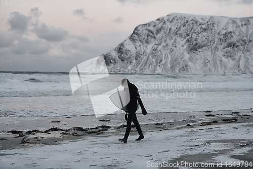 Image of Arctic surfer going by beach after surfing