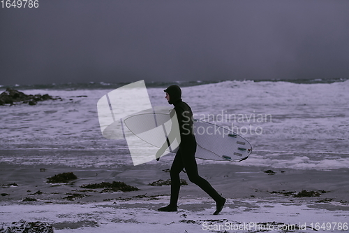 Image of Arctic surfer going by beach after surfing