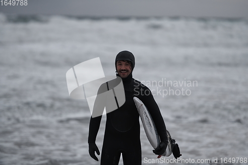 Image of Arctic surfer going by beach after surfing