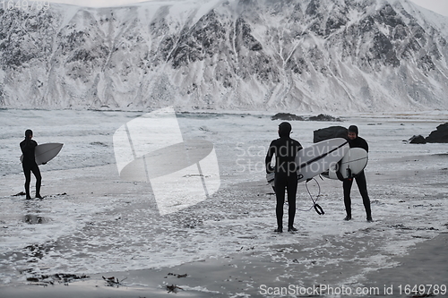 Image of Arctic surfers going by beach after surfing