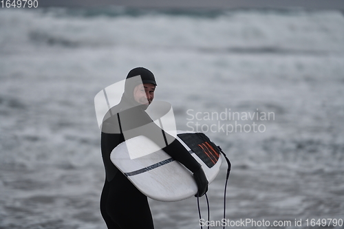 Image of Arctic surfer going by beach after surfing