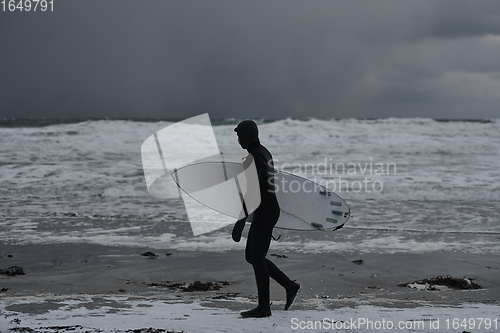 Image of Arctic surfer going by beach after surfing