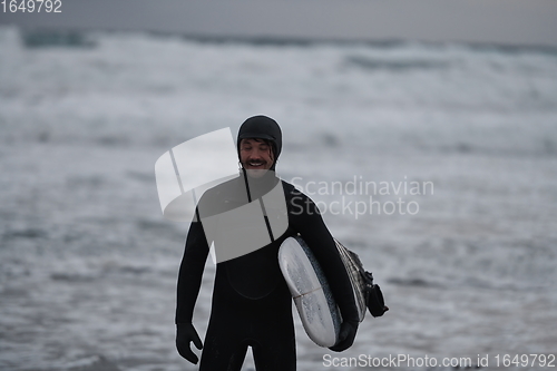 Image of Arctic surfer going by beach after surfing