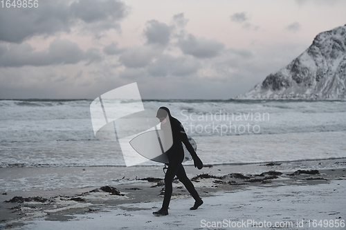 Image of Arctic surfer going by beach after surfing