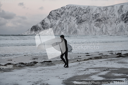 Image of Arctic surfer going by beach after surfing