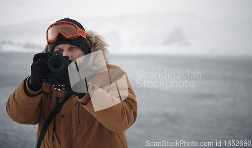 Image of photographer at winter in stormy weather wearing warm fur jacket
