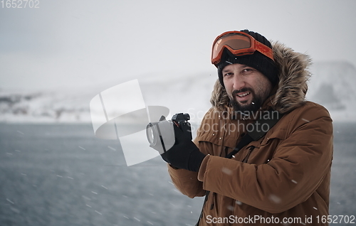 Image of photographer at winter in stormy weather wearing warm fur jacket