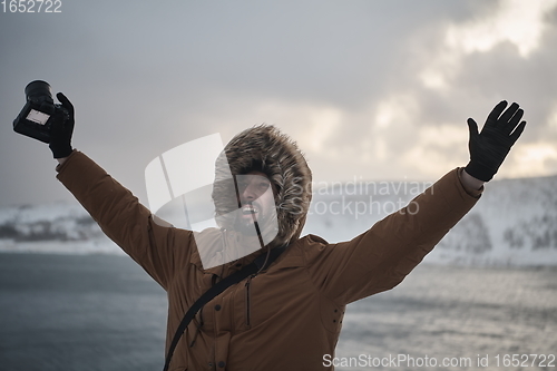 Image of photographer at winter in stormy weather wearing warm fur jacket