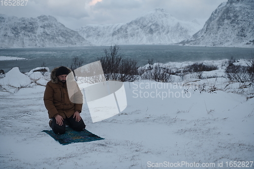 Image of Muslim traveler praying in cold snowy winter day