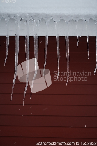 Image of icicles on the roof of a red house in Norway