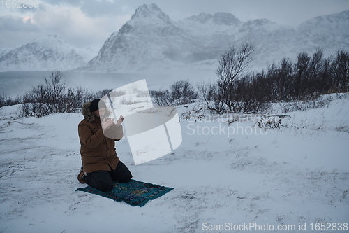 Image of Muslim traveler praying in cold snowy winter day