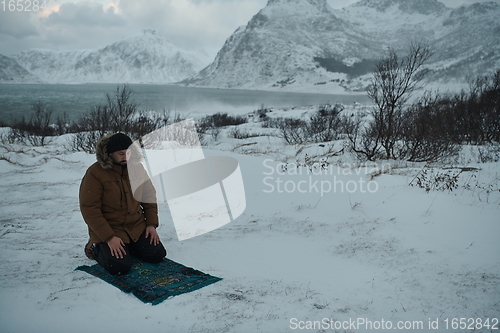 Image of Muslim traveler praying in cold snowy winter day