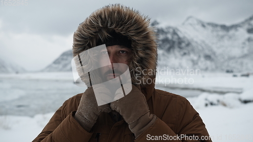 Image of man at winter in stormy weather wearing warm fur jacket