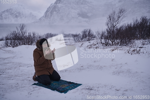 Image of Muslim traveler praying in cold snowy winter day