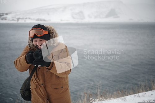 Image of photographer at winter in stormy weather wearing warm fur jacket