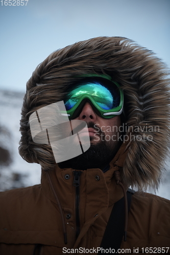 Image of man at winter in stormy weather wearing warm fur jacket