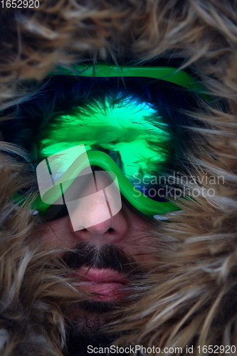 Image of man at winter in stormy weather wearing warm fur jacket