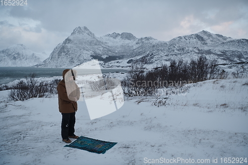 Image of Muslim traveler praying in cold snowy winter day
