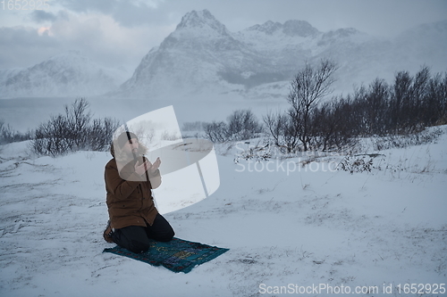 Image of Muslim traveler praying in cold snowy winter day