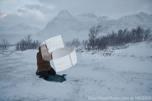 Image of Muslim traveler praying in cold snowy winter day