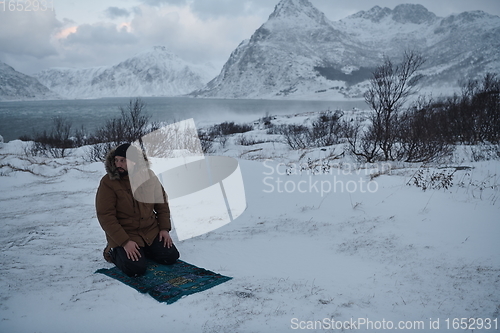 Image of Muslim traveler praying in cold snowy winter day