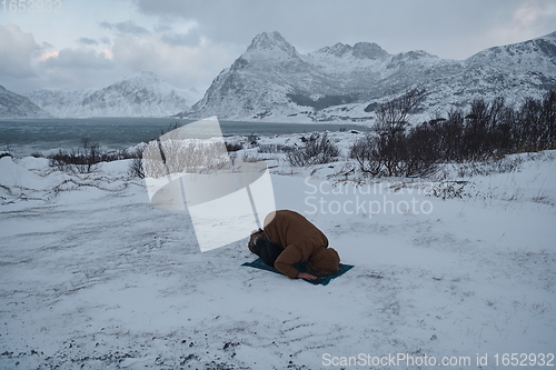 Image of Muslim traveler praying in cold snowy winter day