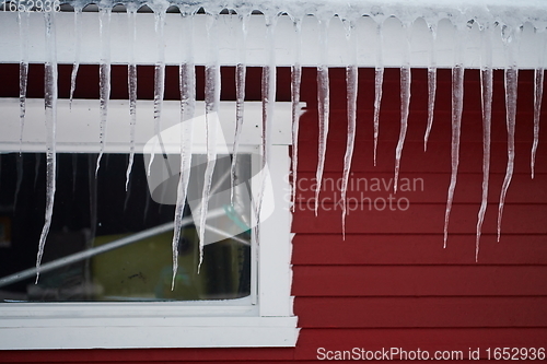 Image of icicles on the roof of a red house in Norway