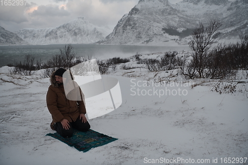 Image of Muslim traveler praying in cold snowy winter day