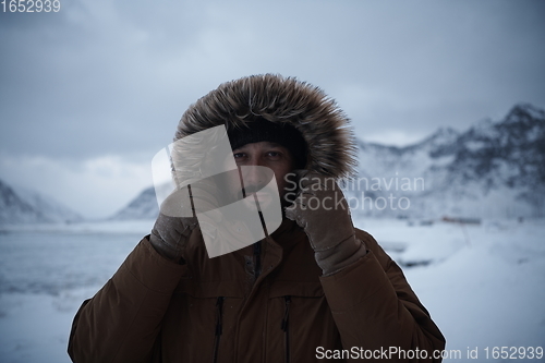 Image of man at winter in stormy weather wearing warm fur jacket