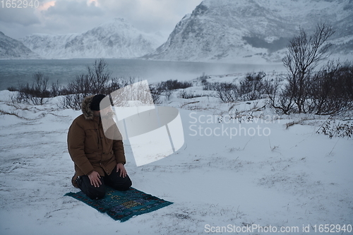 Image of Muslim traveler praying in cold snowy winter day