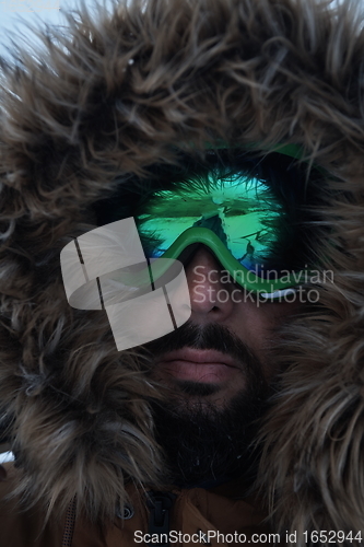 Image of man at winter in stormy weather wearing warm fur jacket