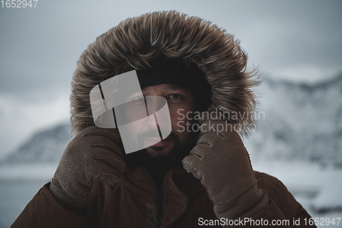 Image of man at winter in stormy weather wearing warm fur jacket