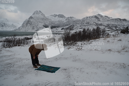 Image of Muslim traveler praying in cold snowy winter day