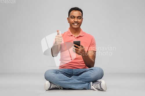 Image of happy indian man with smartphone showing thumbs up