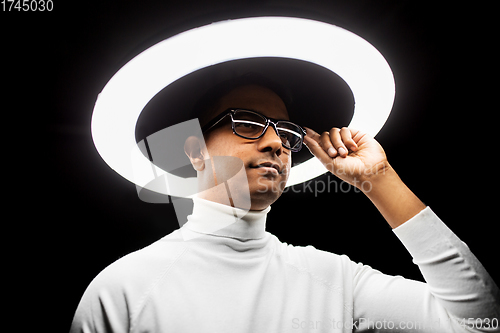 Image of man in glasses under white illumination over black