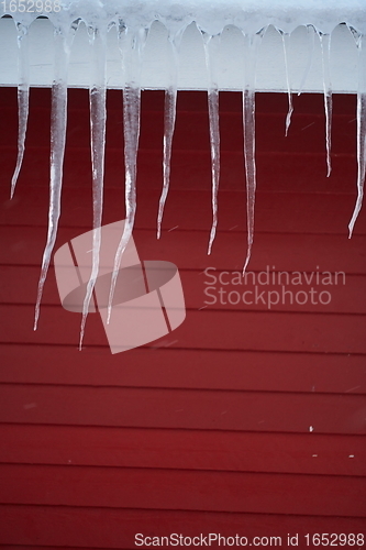 Image of icicles on the roof of a red house in Norway