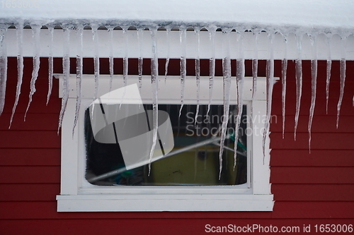 Image of icicles on the roof of a red house in Norway