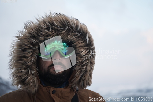 Image of man at winter in stormy weather wearing warm fur jacket