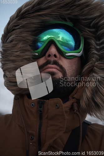 Image of man at winter in stormy weather wearing warm fur jacket