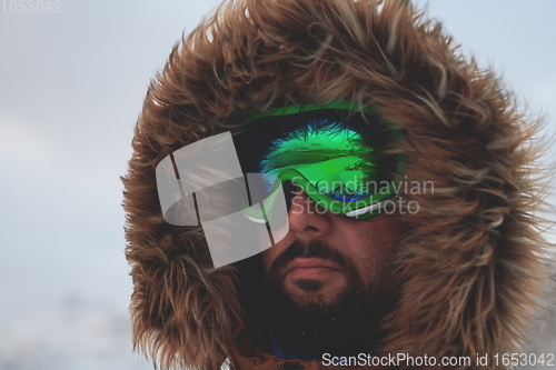 Image of man at winter in stormy weather wearing warm fur jacket