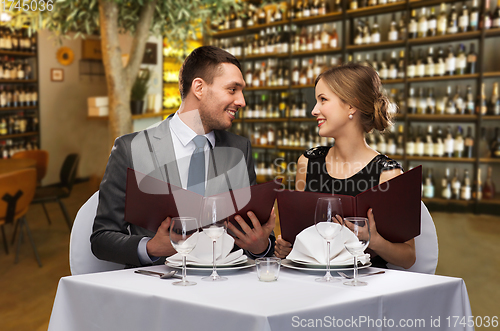 Image of happy couple with menus at restaurant or wine bar