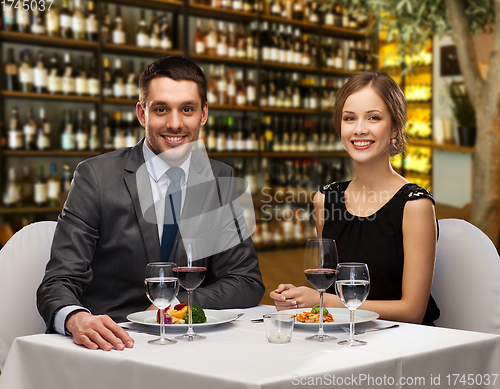 Image of smiling couple with food and wine at restaurant