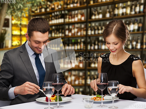 Image of smiling couple eating main course at restaurant