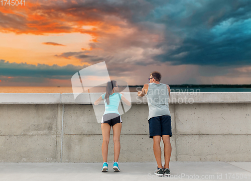 Image of happy couple exercising outdoors at concrete wall