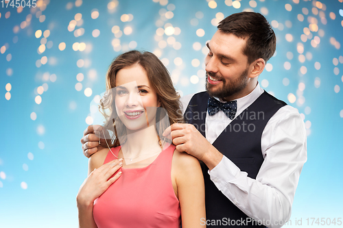 Image of happy man puts necklace on his girlfriend