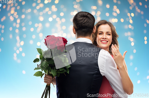 Image of woman with engagement ring and roses hugging man