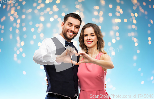 Image of happy couple making hand heart on valentines day